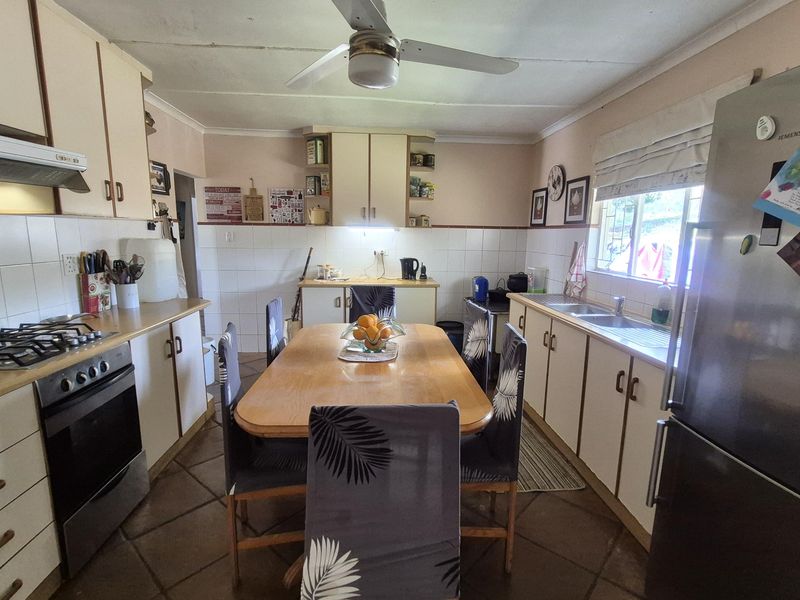 A functional kitchen featuring built-in cabinetry, a gas hob with extractor, double sink, and tiled flooring, offering a practical layout for daily meal preparation.