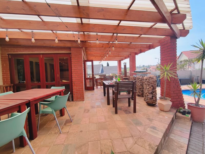 A spacious covered patio featuring a timber pergola, exposed brick pillars, and terracotta tiling, providing an ideal outdoor entertainment area overlooking the pool.
