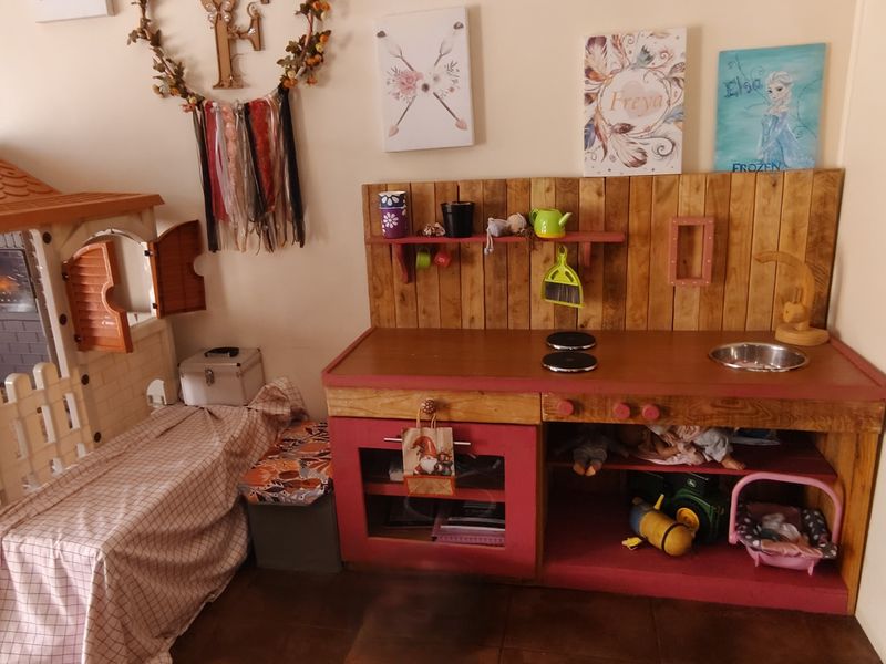 A bedroom interior featuring tiled flooring, currently utilized as a play area with children's furniture and decor.