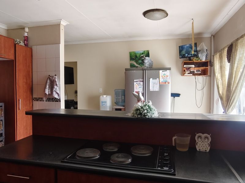A functional kitchen featuring built-in cabinetry, an electric hob, and a breakfast bar, offering a practical layout with potential for modern updates.