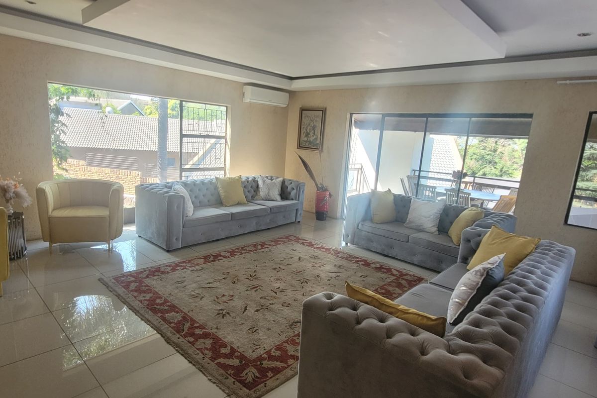 Spacious living room featuring large windows, tiled flooring, a recessed ceiling, and a wall-mounted air conditioning unit with access to an outdoor area.