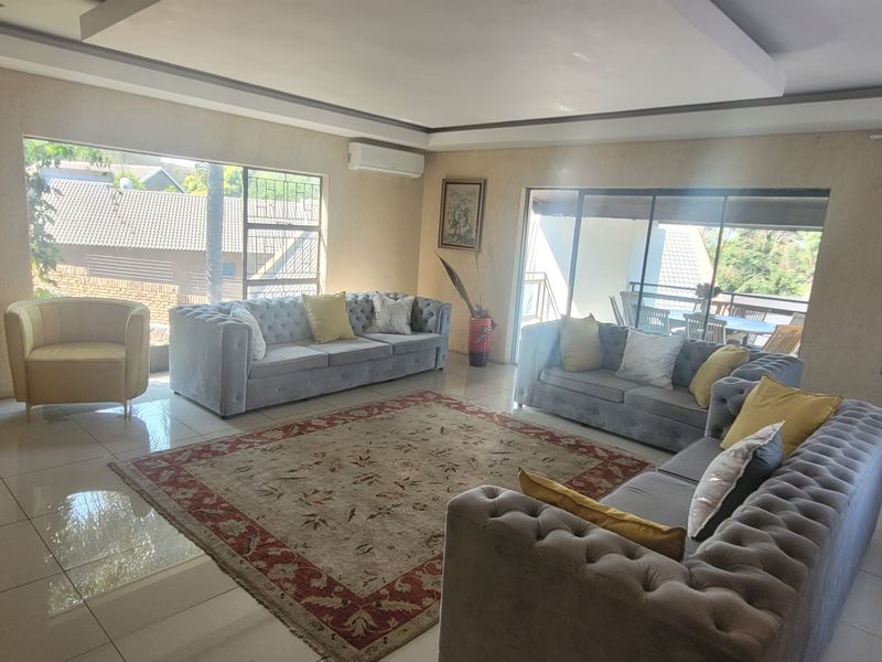 Spacious living room featuring large windows, tiled flooring, a recessed ceiling, and a wall-mounted air conditioning unit with access to an outdoor area.
