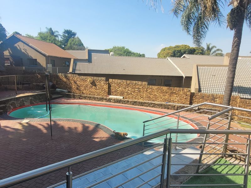 Outdoor pool area featuring a swimming pool, brick paved surround, stainless steel balustrades, and a thatched lapa structure.