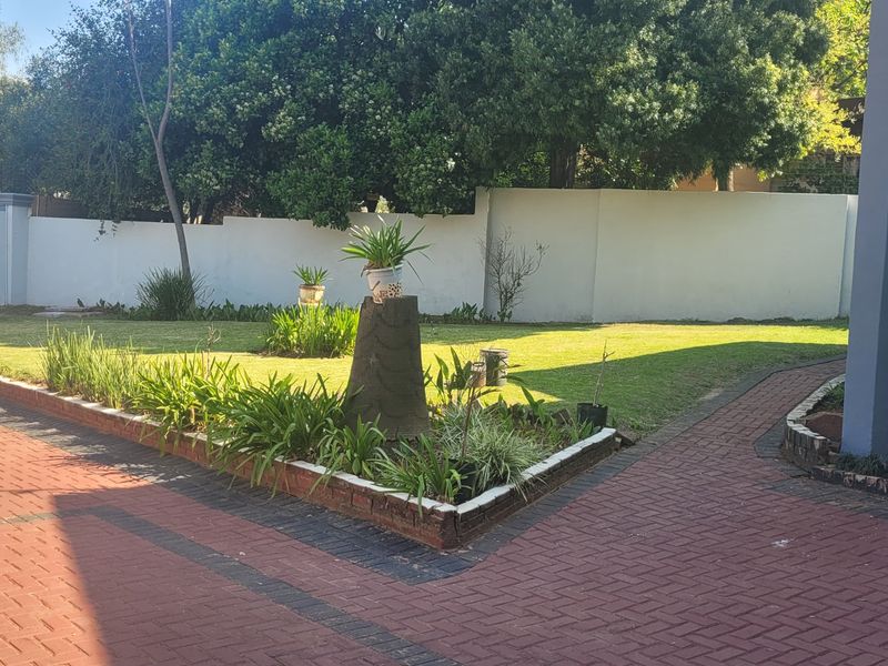 A well-maintained garden area featuring a paved driveway, neat lawn, and perimeter walling, providing a clean and structured outdoor space.