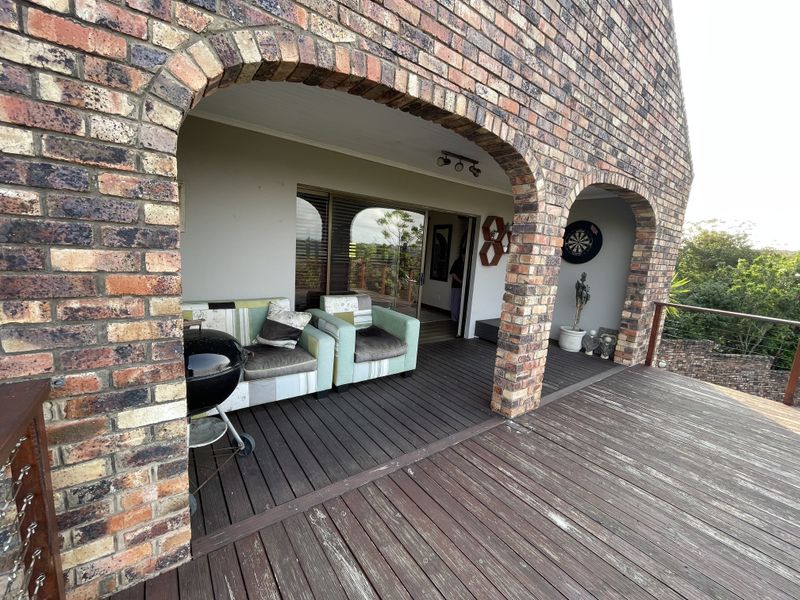 Covered outdoor patio featuring brick archways and timber decking, providing a seamless transition to the interior living space through sliding glass doors.