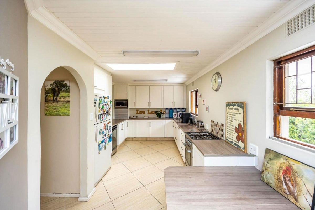 Functional kitchen featuring white built-in cabinetry, gas hob, built-in oven, laminate countertops, and a skylight, with tiled flooring throughout.