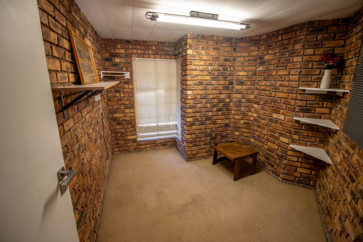 A bedroom featuring exposed brick walls, carpeted flooring, and built-in shelving, offering a rustic aesthetic ready for modernization.