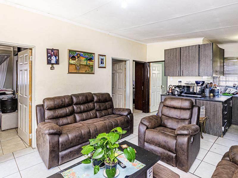 Open-plan living area featuring tiled flooring and a compact kitchen with built-in cabinetry and laminate countertops.