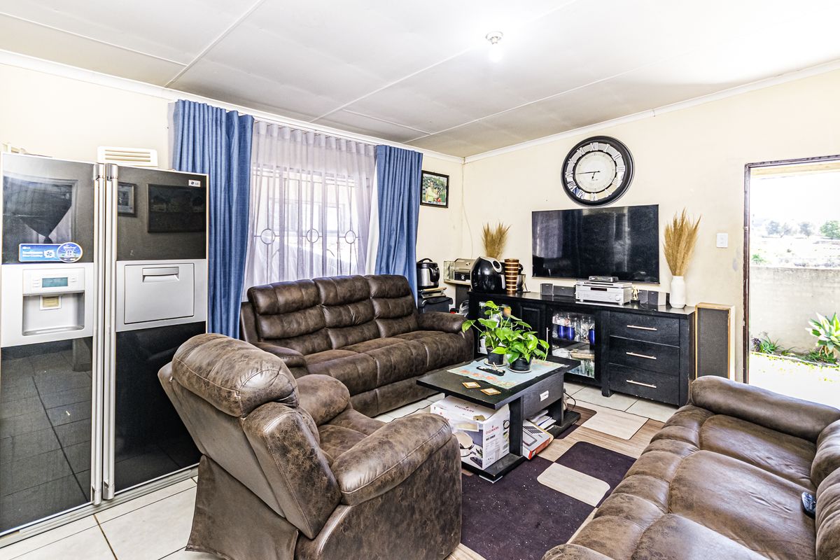 A functional living room featuring tiled flooring and direct access to an outdoor area through a security gate.