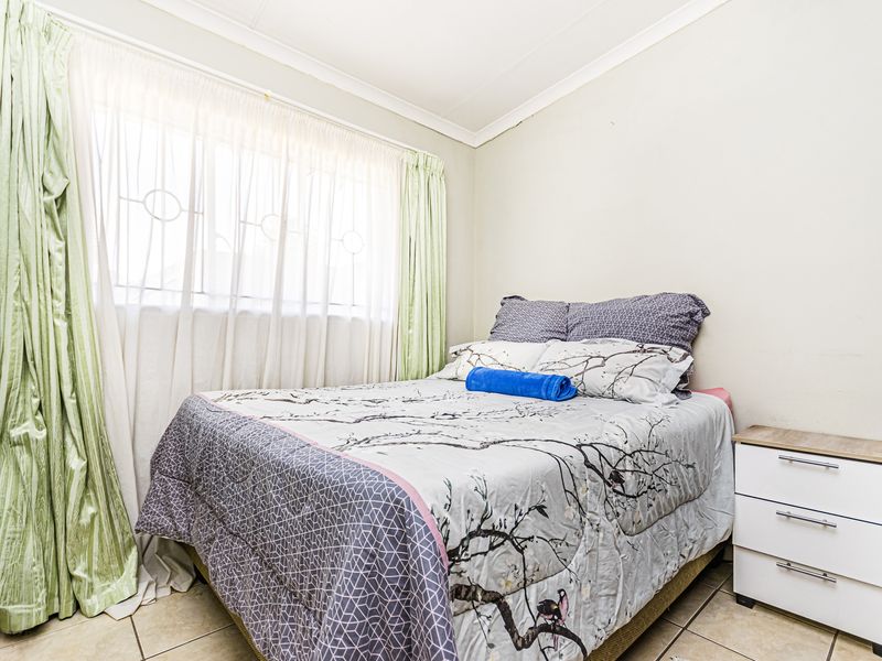 A functional bedroom featuring tiled flooring and neutral wall finishes, providing a comfortable and practical living space.