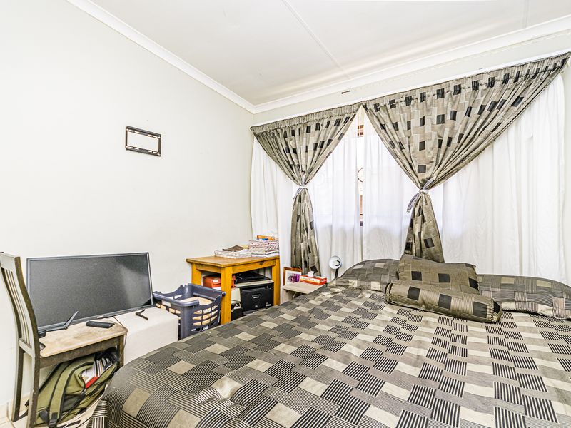 A standard bedroom featuring neutral walls and decorative ceiling cornicing, providing a functional space for rest.