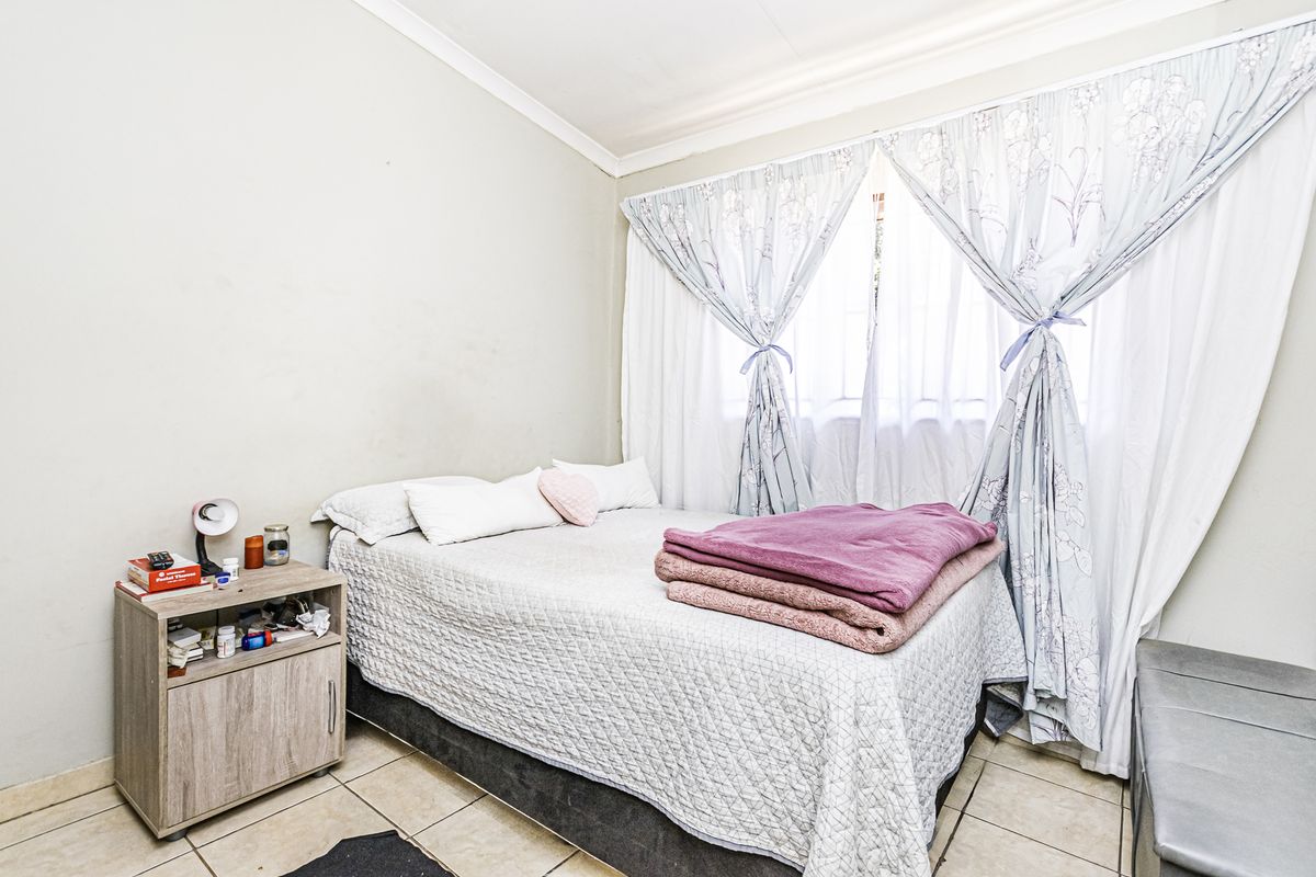 A functional bedroom featuring tiled flooring and neutral wall finishes, providing a simple and practical living space.