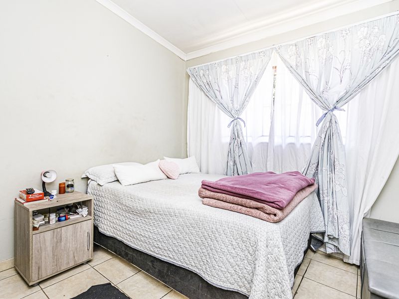 A functional bedroom featuring tiled flooring and neutral wall finishes, providing a simple and practical living space.