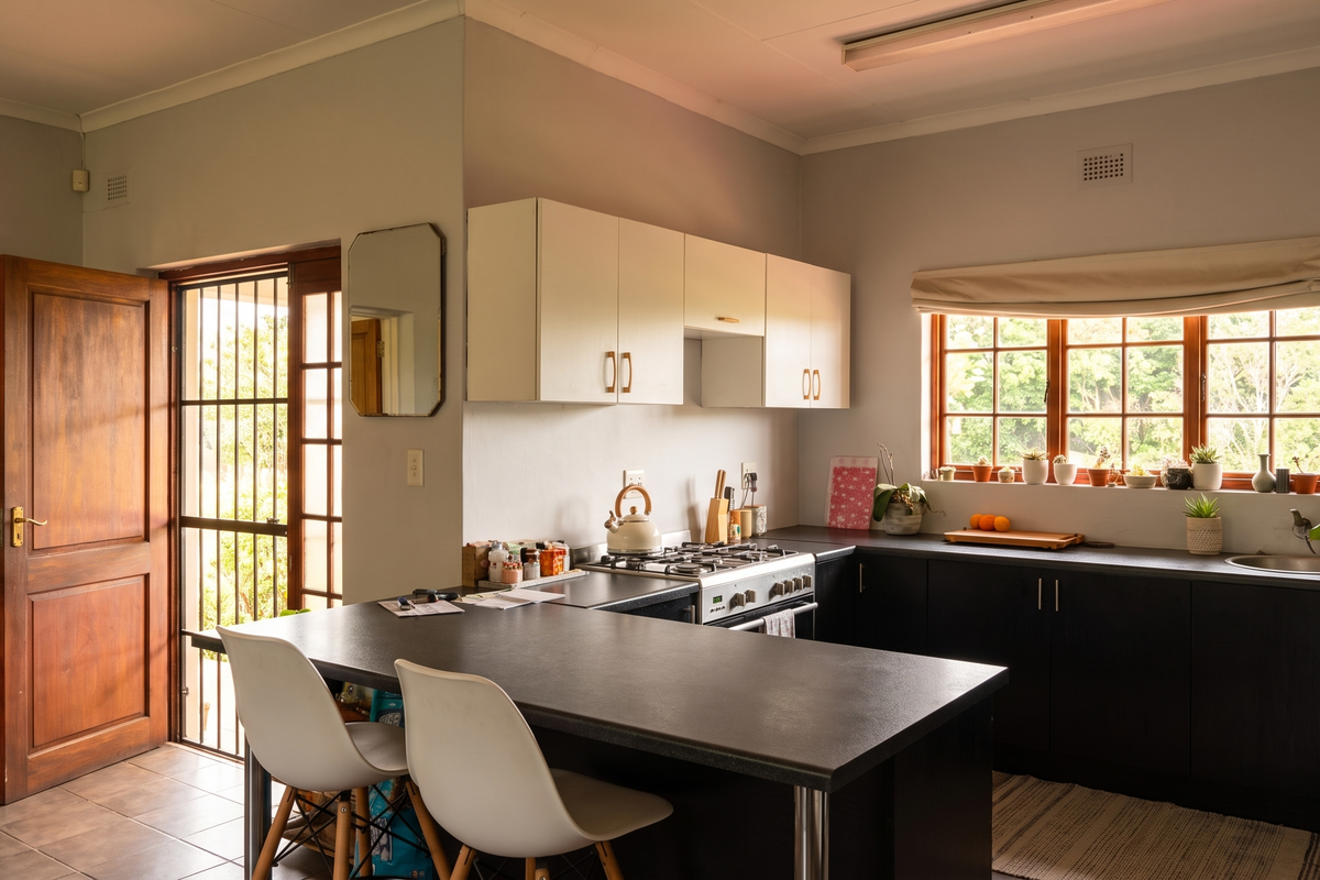 A functional kitchen featuring dark cabinetry, light countertops, a gas hob, and an integrated breakfast bar, with direct access to the exterior.