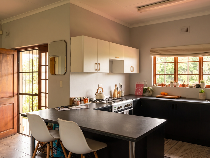 A functional kitchen featuring dark cabinetry, light countertops, a gas hob, and an integrated breakfast bar, with direct access to the exterior.