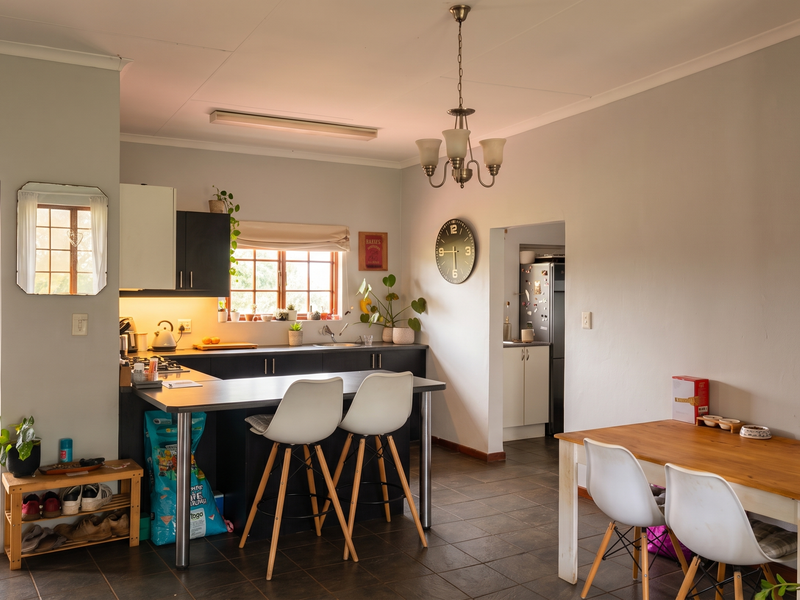 Open plan kitchen and dining area featuring dark cabinetry, a breakfast island, tiled flooring, and direct access to an outdoor patio through a wooden door.