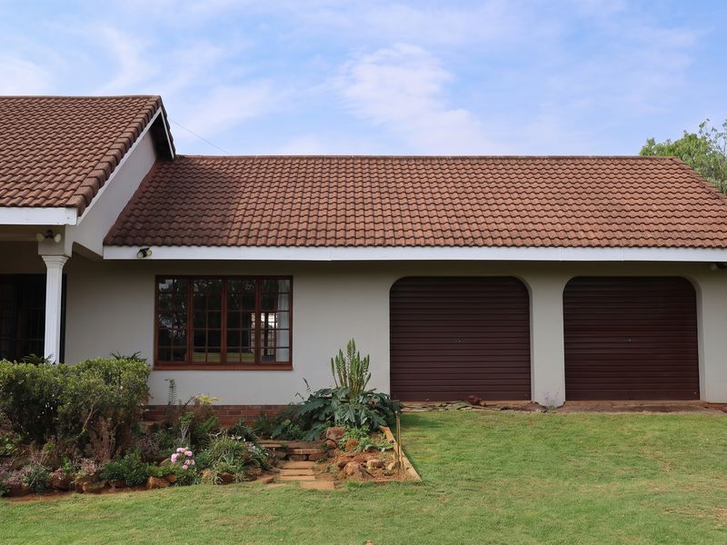 Front elevation of a house featuring a double garage, tiled roof, and established garden area.