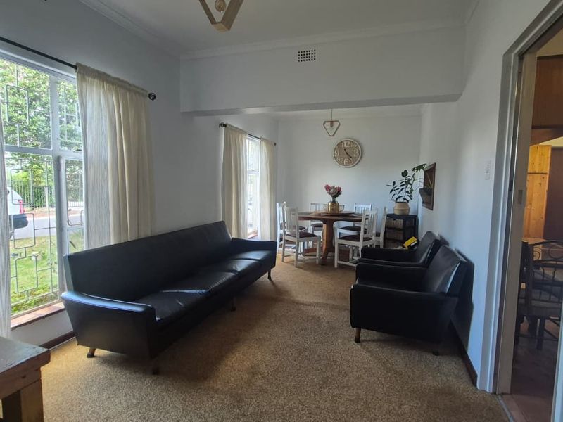 Open plan living and dining area featuring large windows, neutral walls, and carpet flooring, offering a functional space for relaxation and meals.