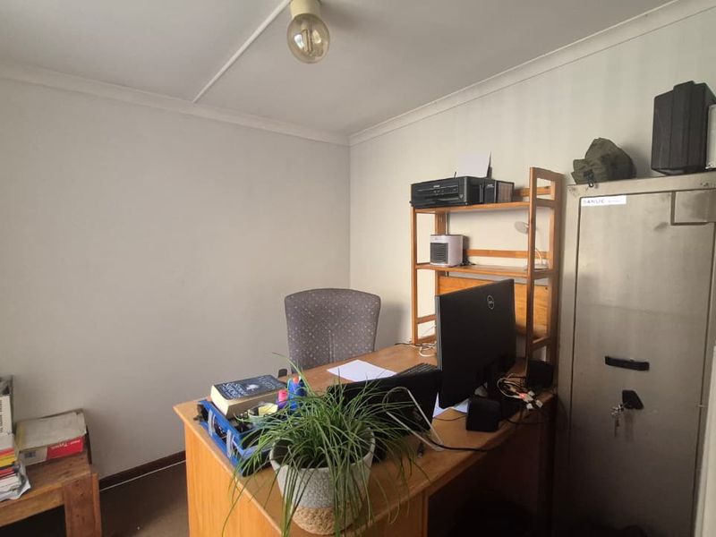A functional home office space featuring a built-in safe and neutral wall finishes, suitable for a dedicated workspace or study.