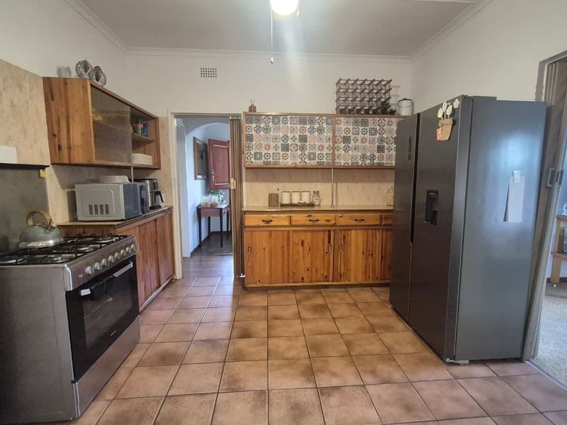 A functional kitchen featuring wooden cabinetry, tiled flooring, a gas stove, and a decorative tiled backsplash, offering a traditional aesthetic.