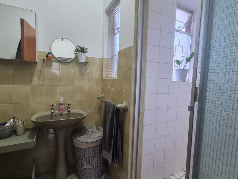 A functional bathroom featuring a pedestal basin, tiled wall finishes, and a separate shower enclosure with a glass door.