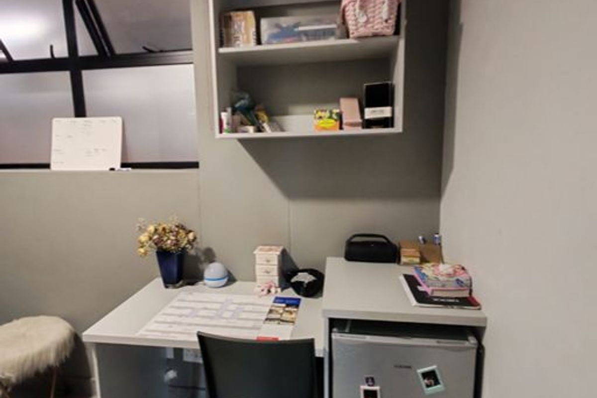 A functional bedroom space featuring built-in shelving, tiled flooring, and an awning window, providing a practical area for study or storage.