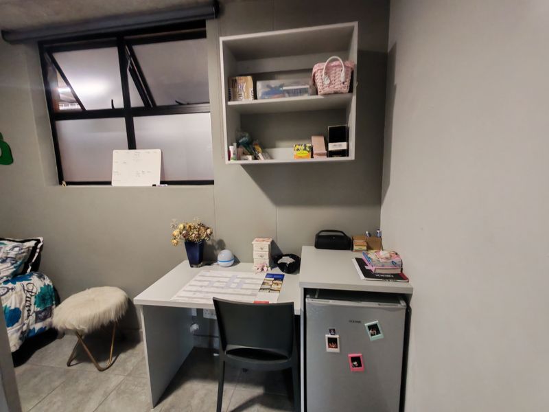 A bedroom featuring tiled flooring, an awning window, and built-in wall shelving, providing a functional space for study or storage.