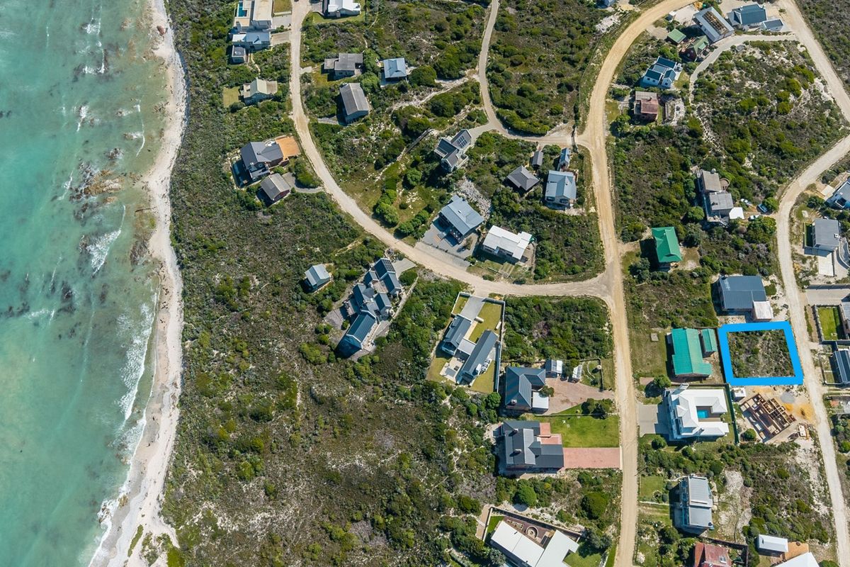 An aerial view of a coastal residential estate, highlighting the surrounding landscape, road infrastructure, and the specific vacant land plot.