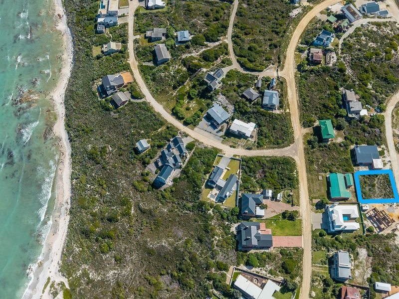 An aerial view of a coastal residential estate, highlighting the surrounding landscape, road infrastructure, and the specific vacant land plot.