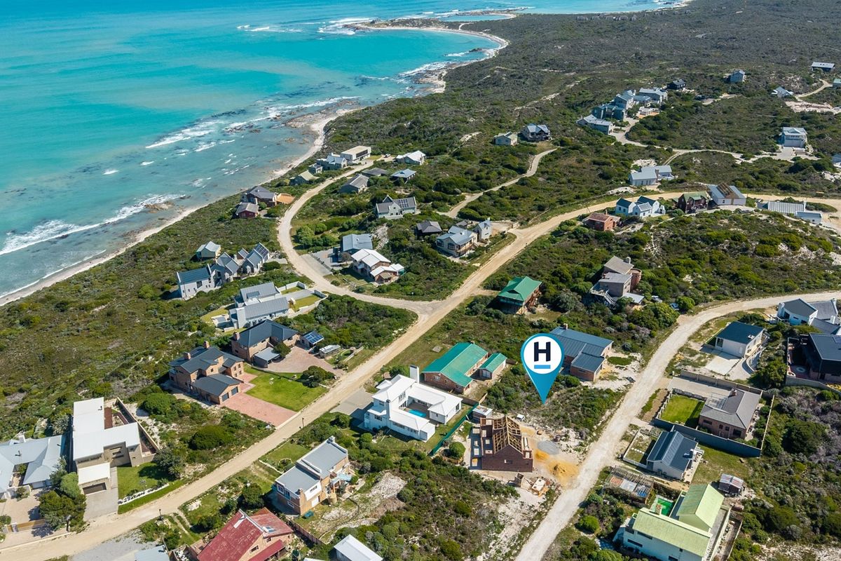 Aerial view of a coastal residential estate featuring established homes and vacant plots near the ocean.