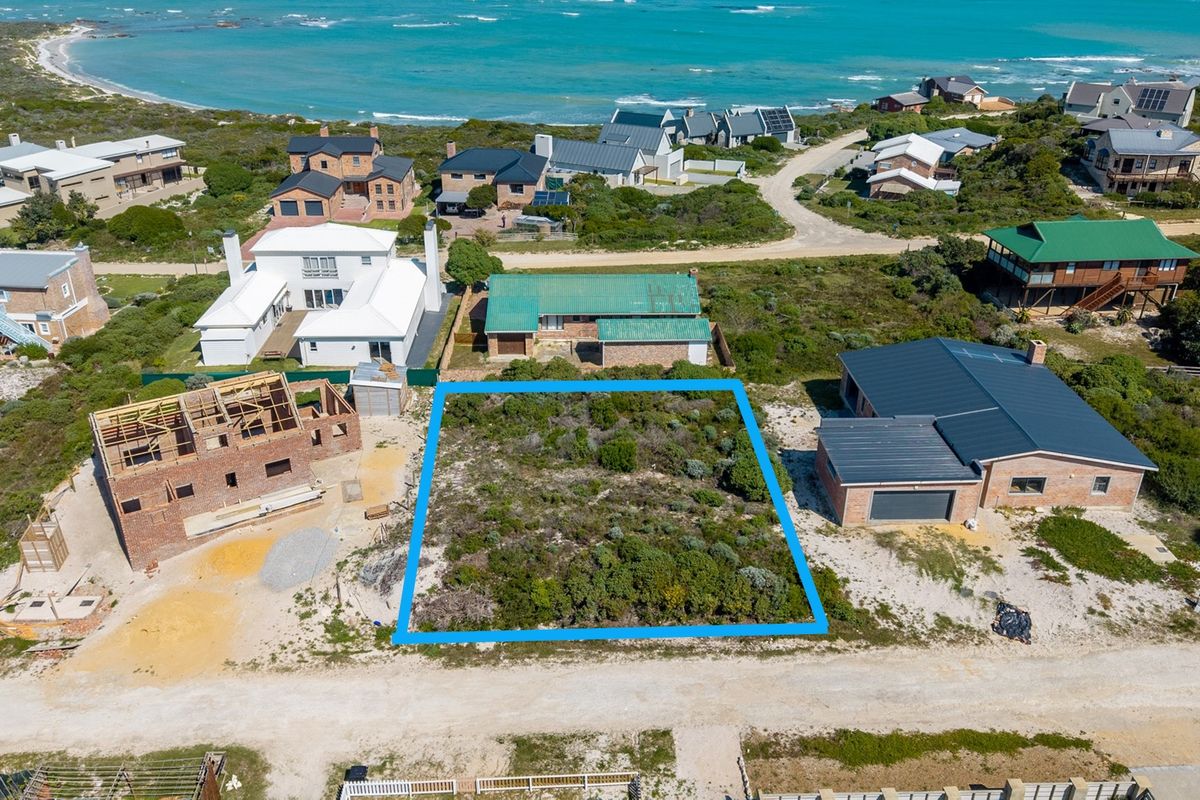 An aerial view of a vacant residential plot situated in a coastal neighborhood, ready for development.