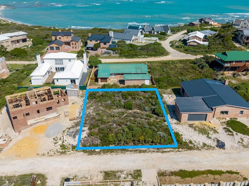 An aerial view of a vacant residential plot situated in a coastal neighborhood, ready for development.