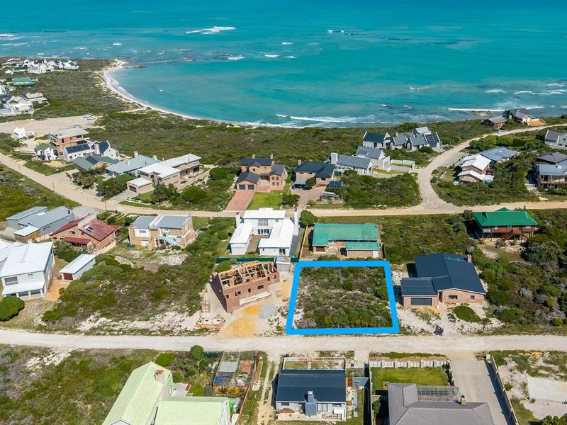 An aerial view of a vacant residential plot situated in a coastal neighborhood, highlighting its proximity to the ocean and surrounding residential development.
