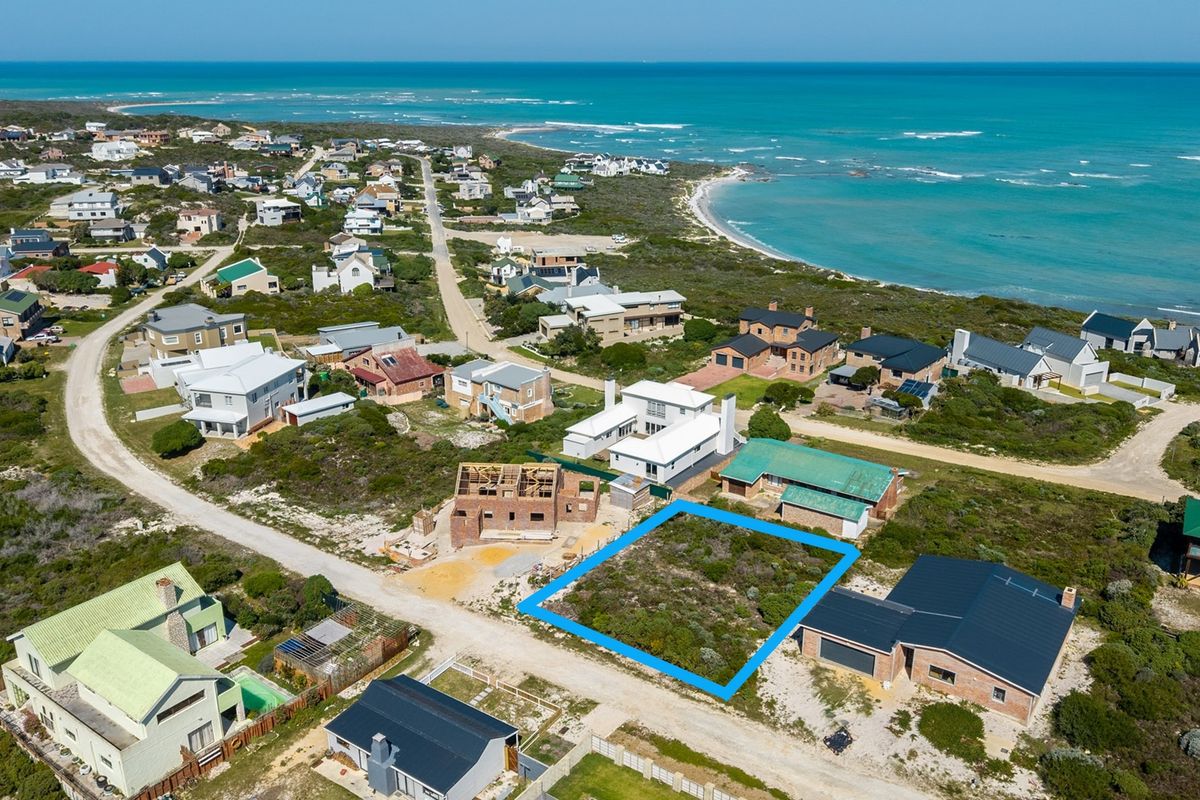 An aerial view of a vacant residential land plot situated in a coastal neighborhood, offering proximity to the ocean.
