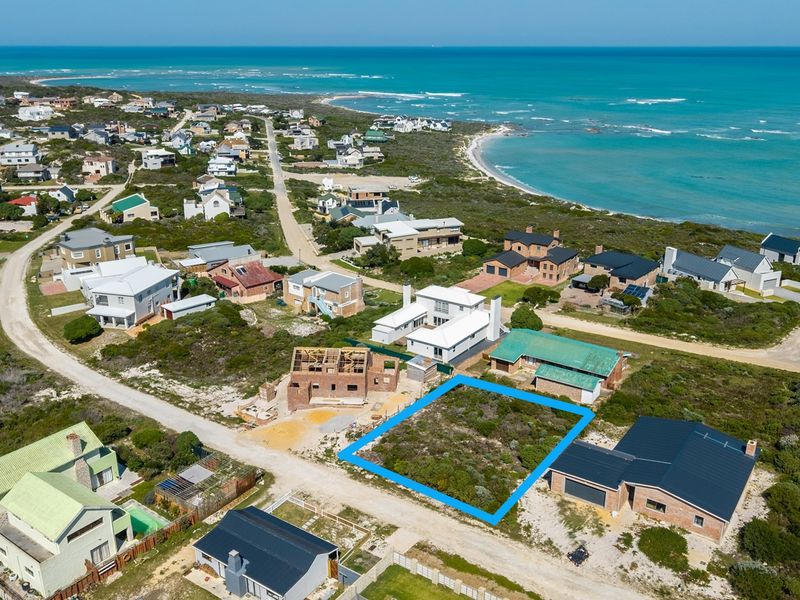 An aerial view of a vacant residential land plot situated in a coastal neighborhood, offering proximity to the ocean.