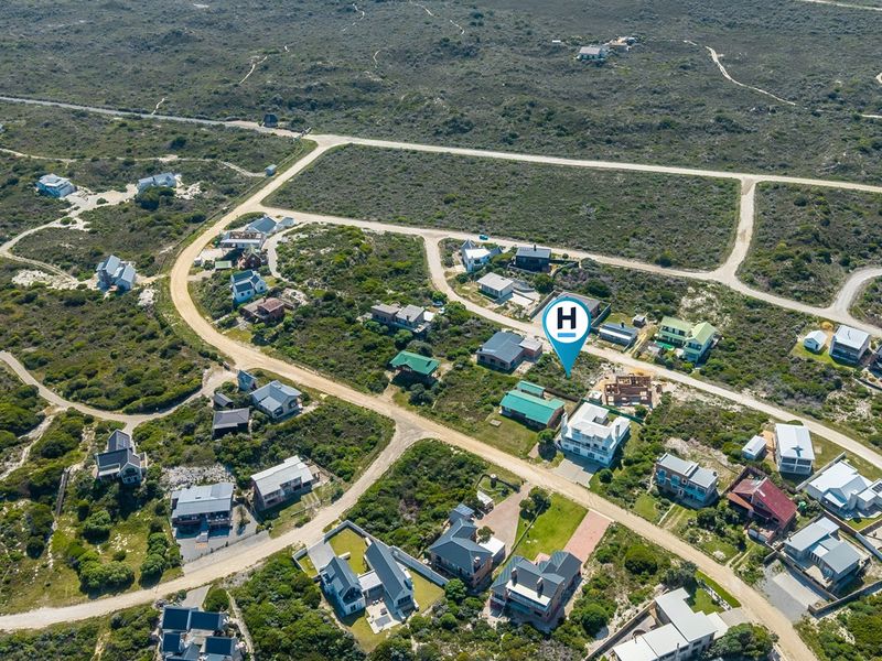 Aerial view of a coastal residential development area featuring established plots, natural vegetation, and surrounding road infrastructure.
