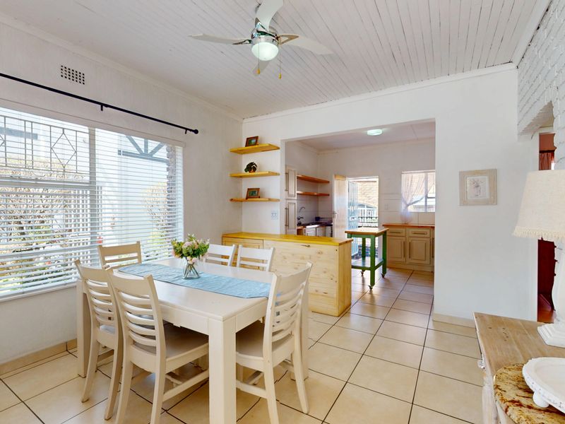 Open plan dining area featuring tiled floors, a timber ceiling, and a view through to the kitchen area with built-in cabinetry.