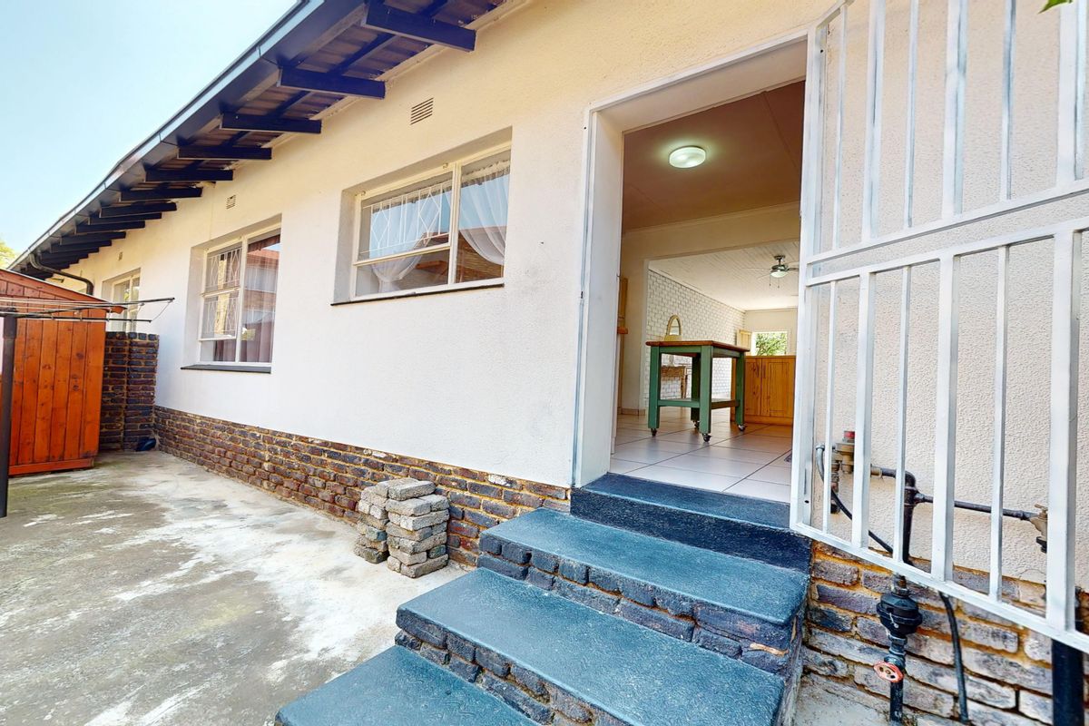 Rear exterior view of the townhouse featuring a concrete patio area, brick facade, and direct access into the interior living space via security gate.