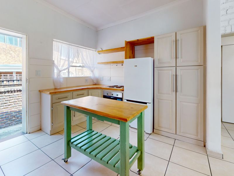 A functional kitchen featuring built-in cabinetry, wooden countertops, a built-in oven, and tiled flooring with direct access to an outdoor area.