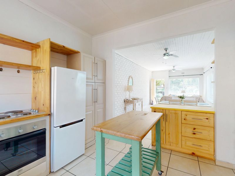 Open-plan kitchen and dining area featuring tiled floors, built-in cabinetry, and an exposed brick wall, creating a functional and connected living space.