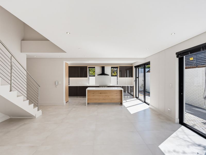 Spacious open-plan kitchen and living area featuring modern cabinetry, a central island, tiled floors, and direct access to the outdoor space via sliding doors.