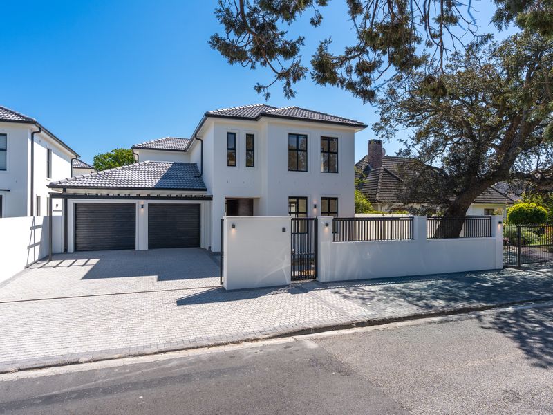 Modern double-storey residence featuring a paved driveway, double garage, and secure boundary wall with gated entrance.