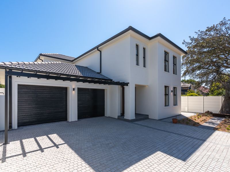 Modern double-storey home featuring a paved driveway, double garage with pergola, and clean white exterior finishes.