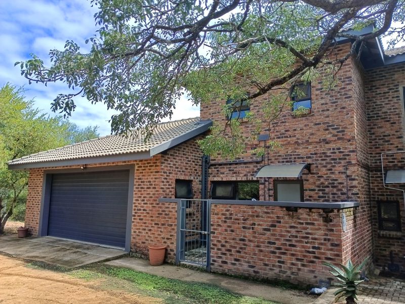 Front elevation of a double-story face brick house featuring an integrated garage, tiled roof, and secure gated entrance.