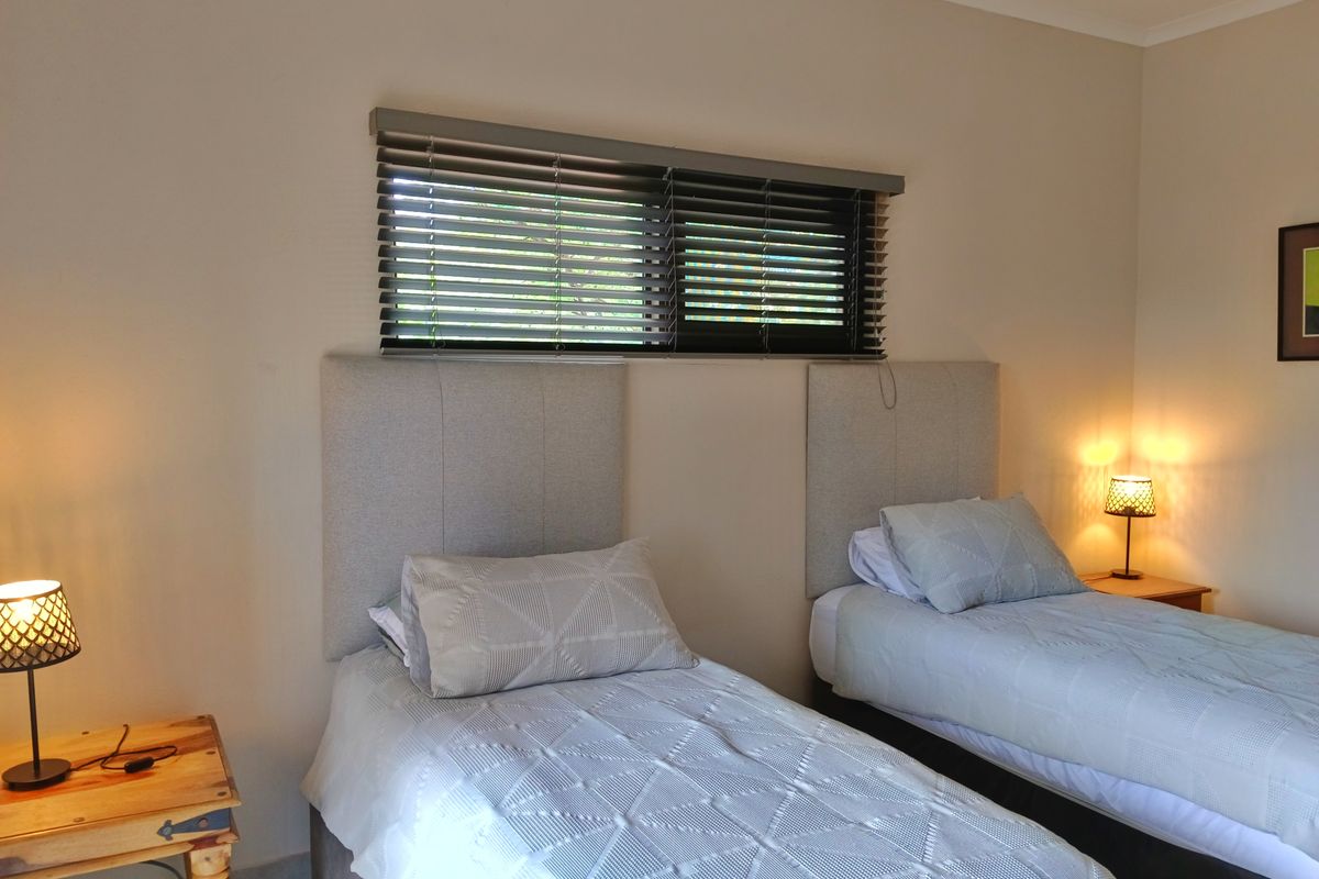 A well-maintained bedroom featuring neutral walls, recessed downlighting, and dark venetian blinds, providing a clean and functional sleeping space.