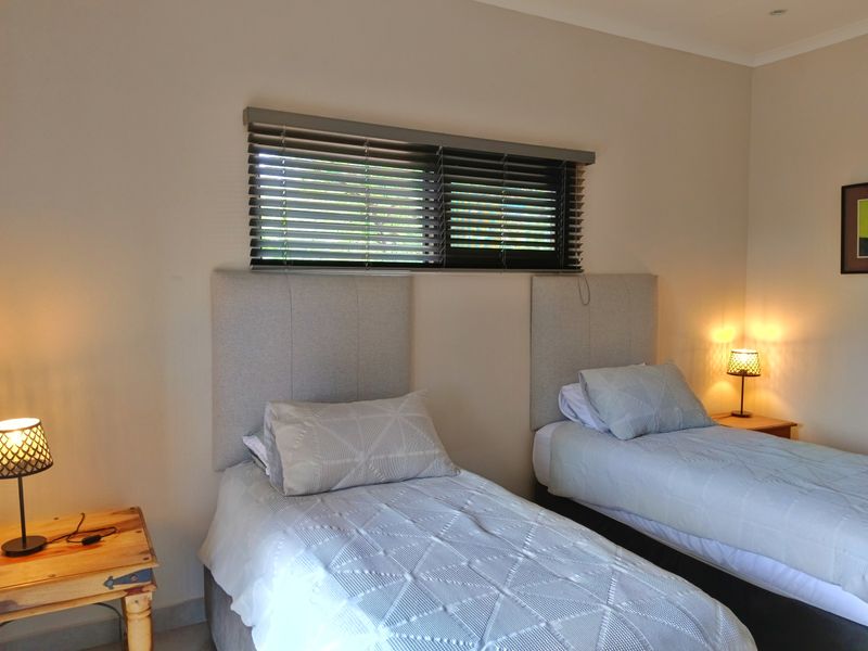 A well-maintained bedroom featuring neutral walls, recessed downlighting, and dark venetian blinds, providing a clean and functional sleeping space.