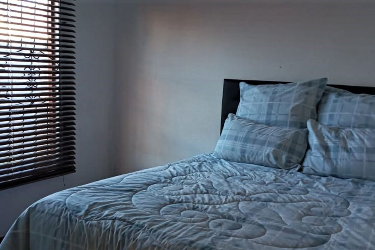 A bedroom featuring a window with fitted venetian blinds.