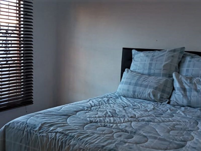 A bedroom featuring a window with fitted venetian blinds.
