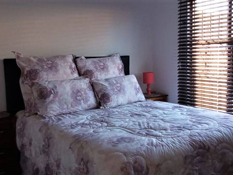 A functional bedroom featuring large windows with fitted venetian blinds, providing natural light and a neutral backdrop for personalization.