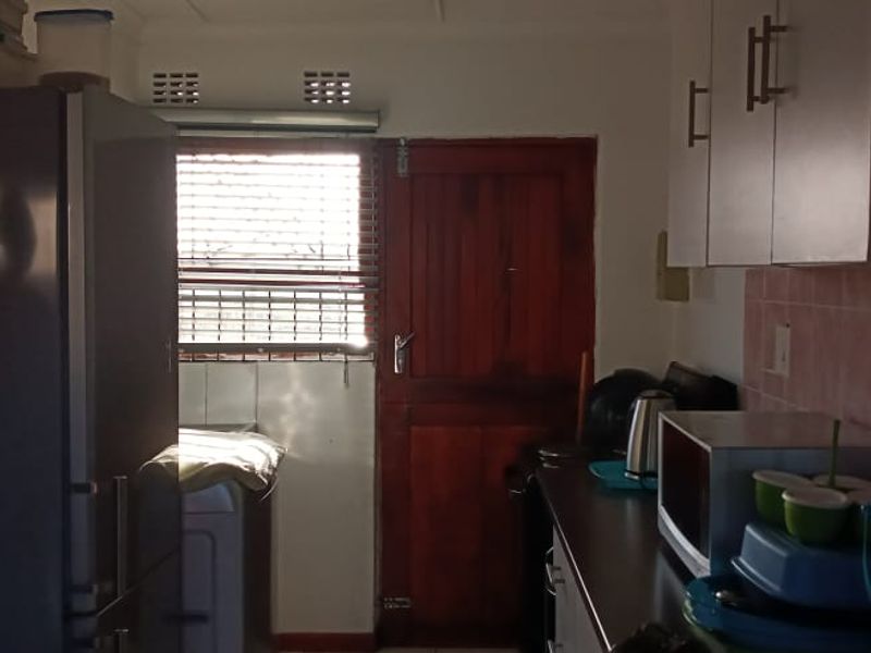 A functional kitchen space featuring built-in cabinetry, tiled backsplash, and direct access to an exterior door.